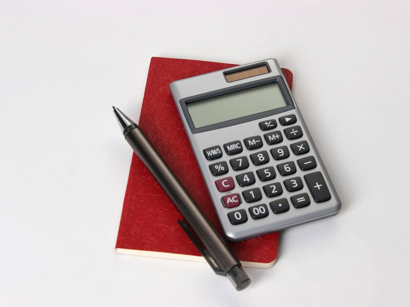 Calculator and pen resting on a red notebook