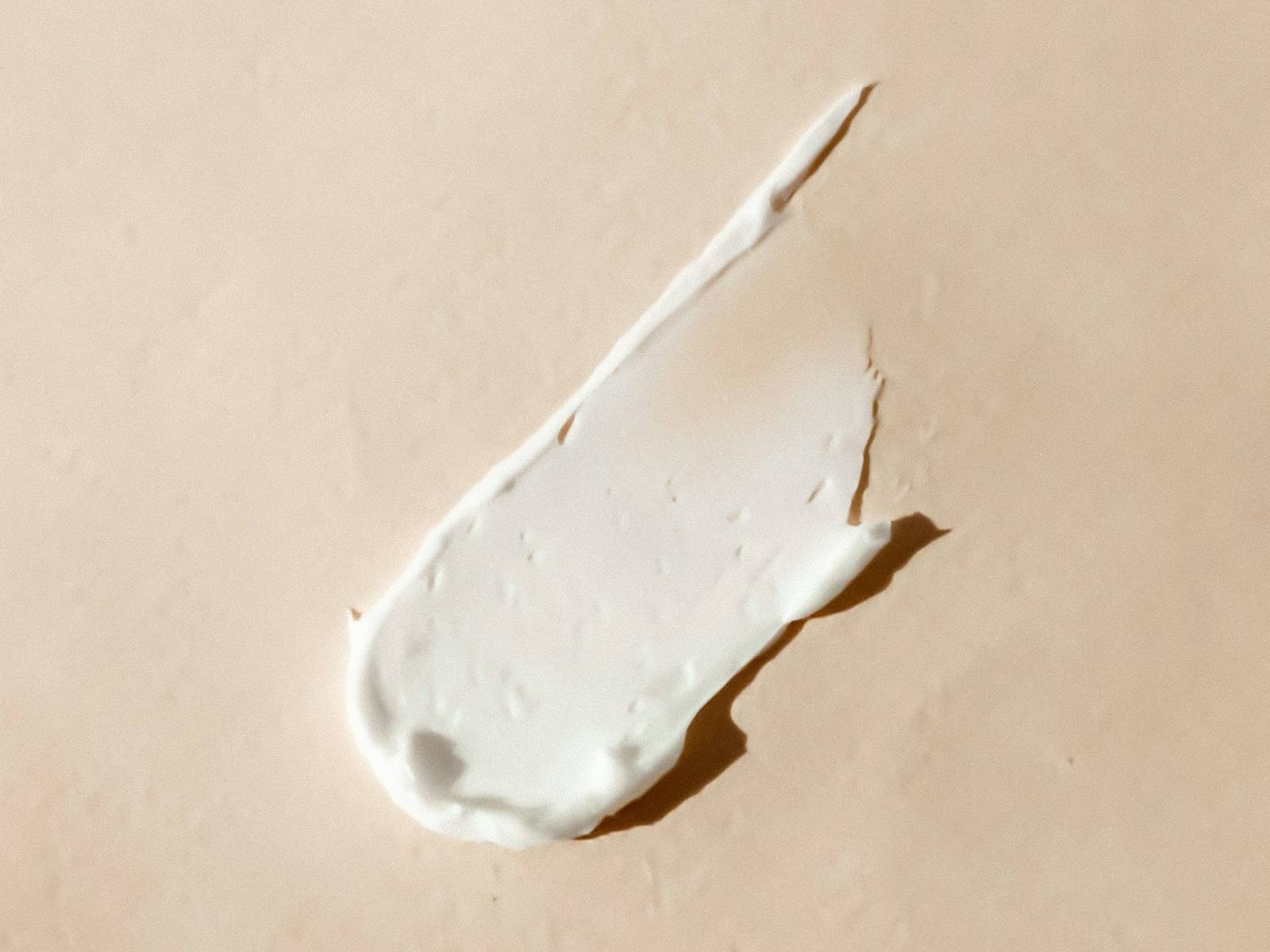 Swatch of rich cream on a warm beige background
