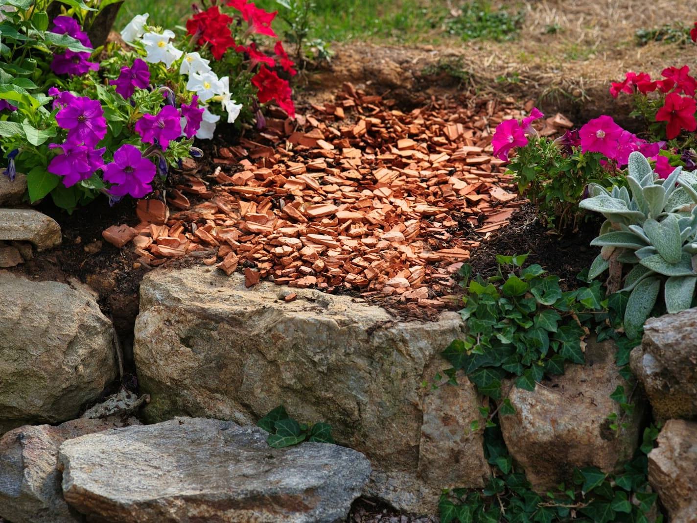 Garden bed edged with large rocks, mulch and flowering plants
