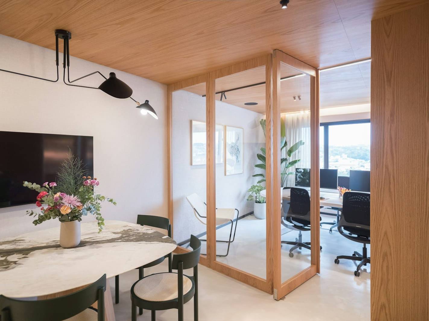 Light-filled office with a timber-framed glass meeting room, plants and a round table