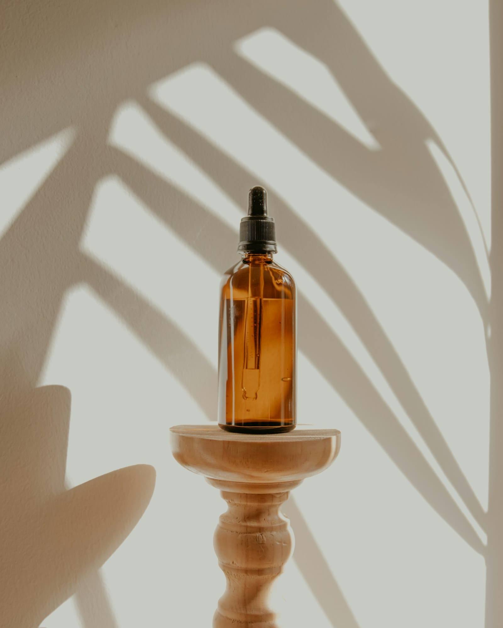 Amber glass dropper bottle on a timber stand with soft palm-leaf shadows