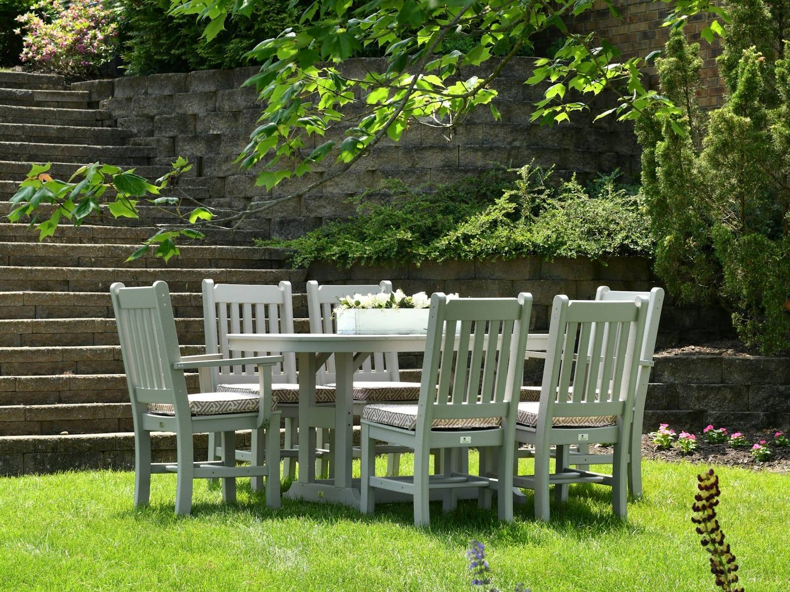 Outdoor dining setting on a lawn below block retaining wall steps