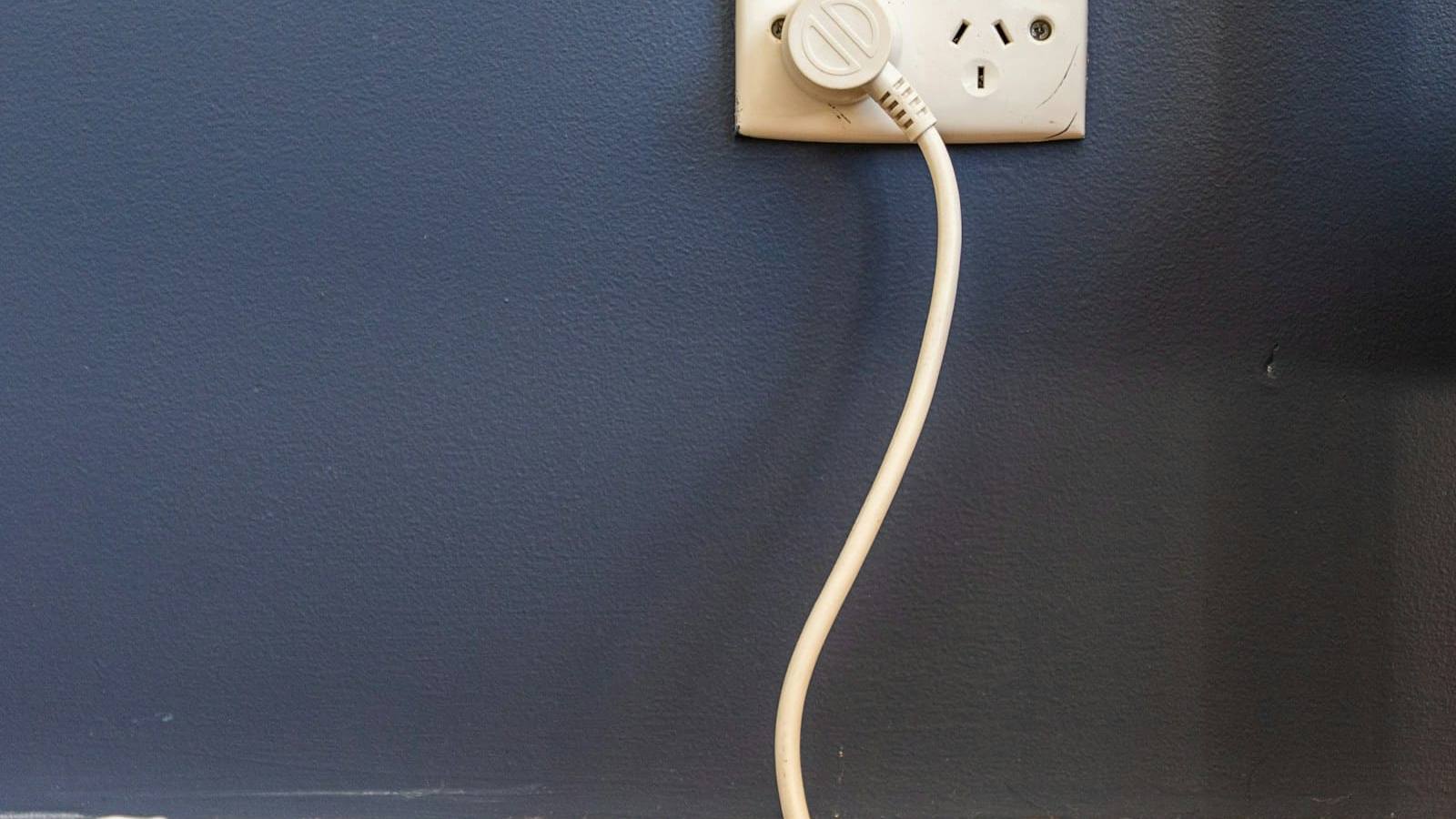 Australian power point on a dark blue wall with a plug in