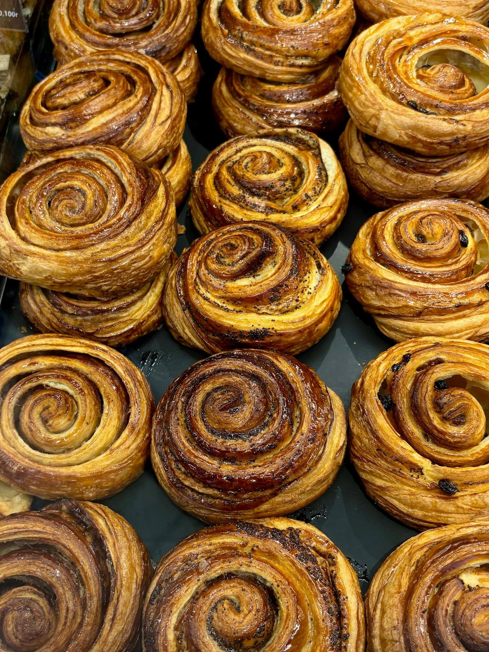 Cinnamon scrolls lined up in a bakery cabinet