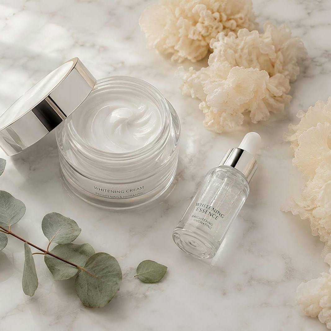 Jar of face cream and a serum bottle on marble with eucalyptus leaves