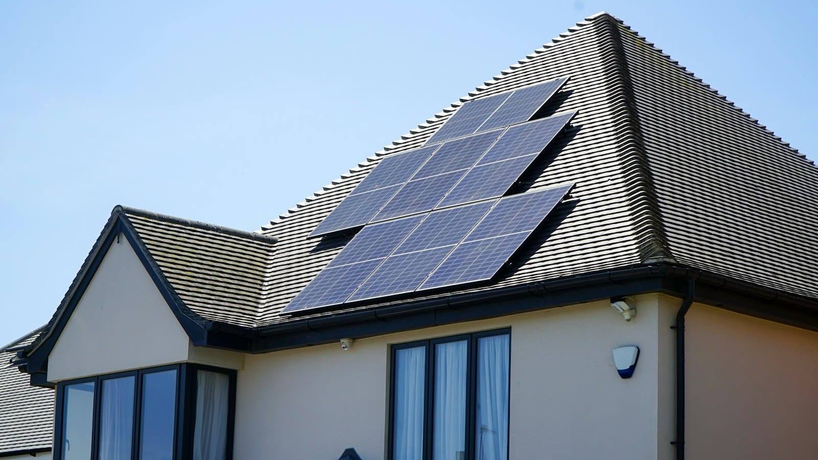 House roof with a row of solar panels against a blue sky