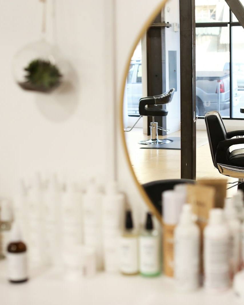 Bright salon studio with a round mirror, styling chair and shelves of products