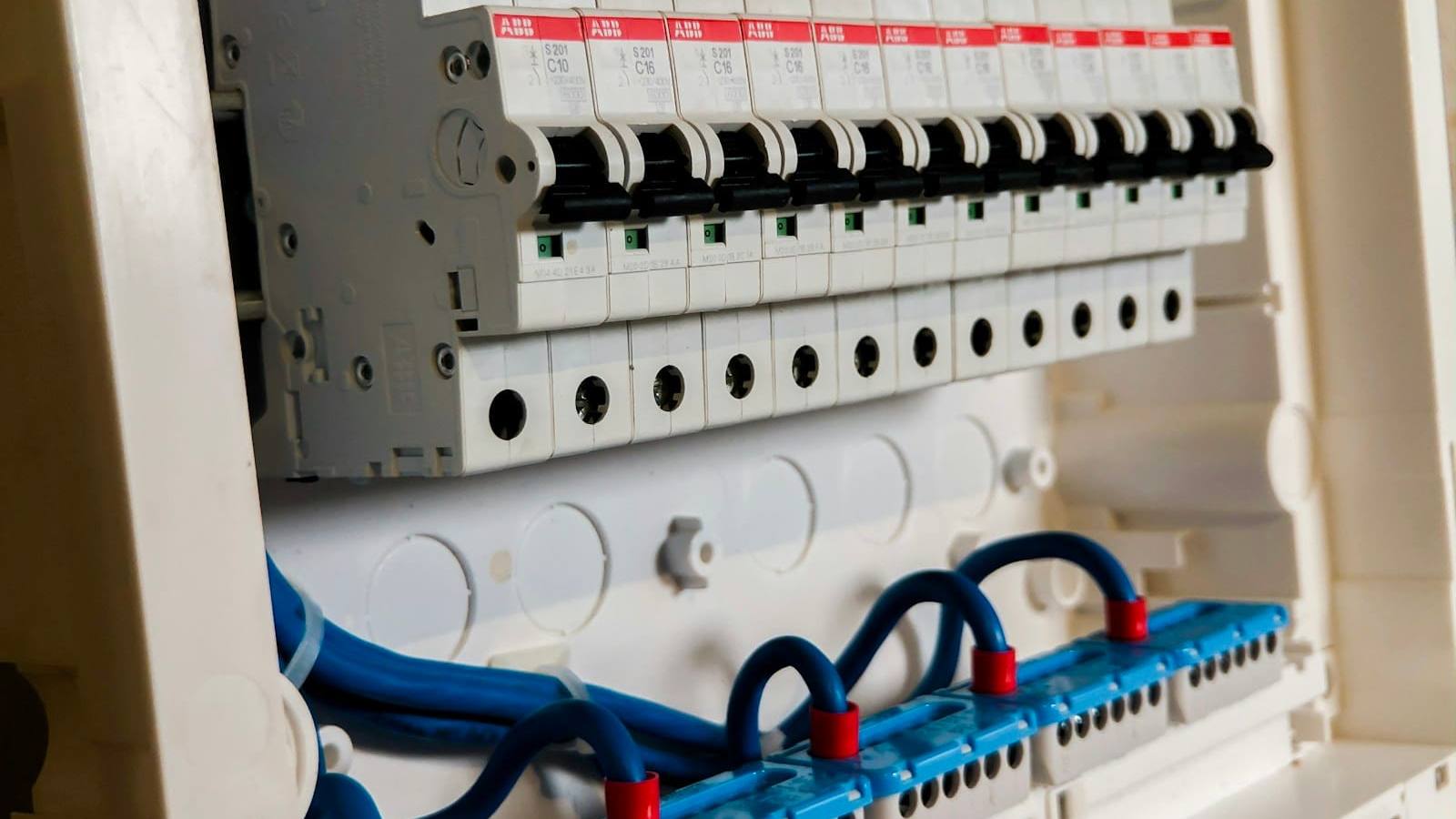 Close-up of white circuit breakers and blue wiring in a switchboard