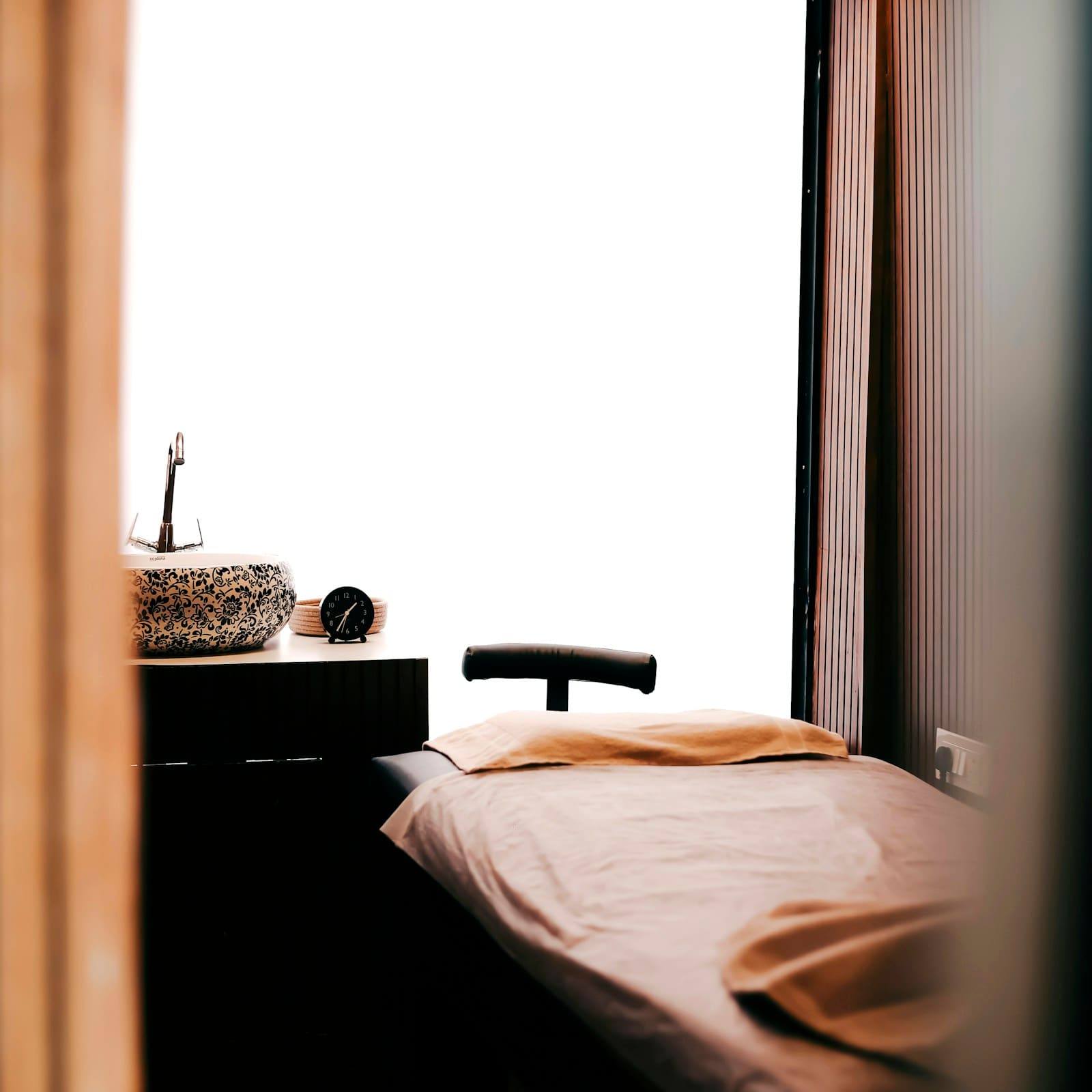 Treatment bed with a soft blush sheet beside a window
